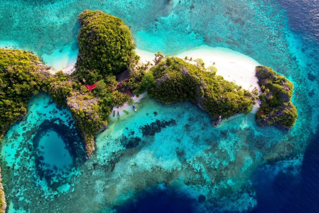 Breathtaking aerial view of a lush tropical island surrounded by turquoise waters in Southwest Papua, Indonesia.