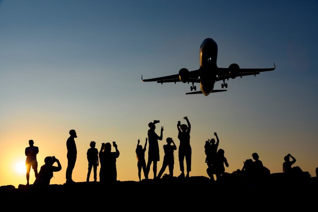 A dynamic silhouette of people photographing an airplane during a vibrant sunset.