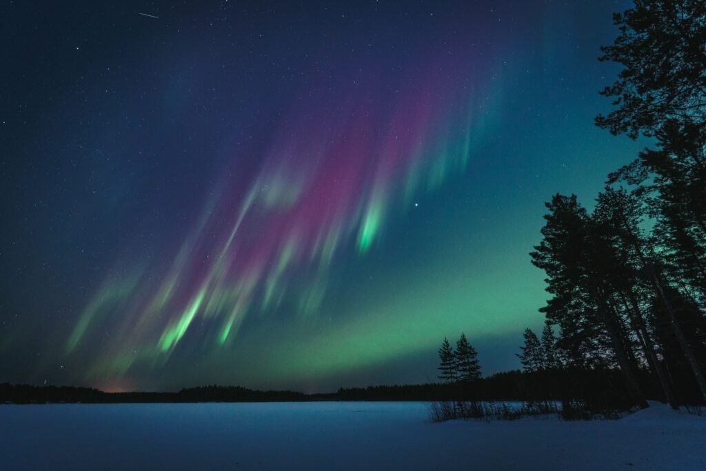 Northern lights illuminate the night sky over a serene lake in Oulu, Finland.