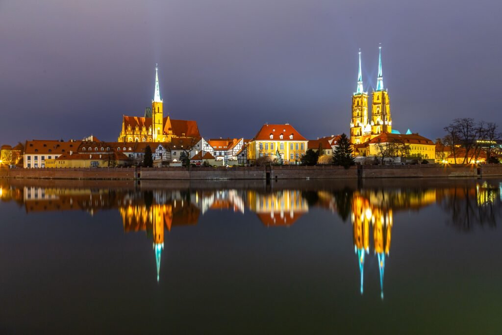 Stunning night view of Wrocław Cathedral illuminated and mirrored in the calm river.