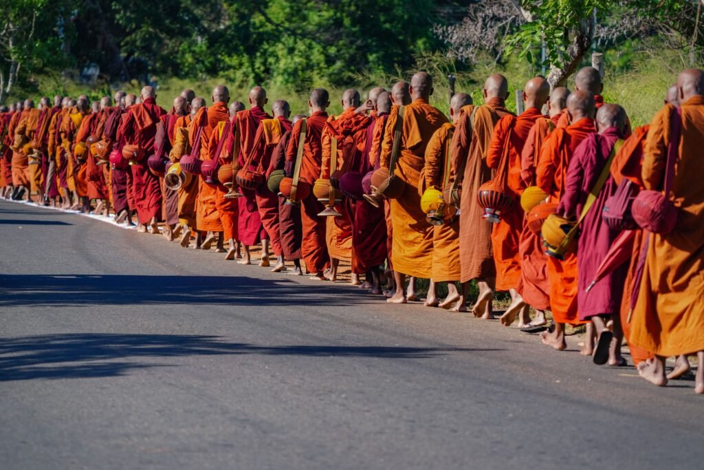 Buddhist monks walk in line during a religious pilgrimage in Sri Lanka, wearing traditional orange robes.