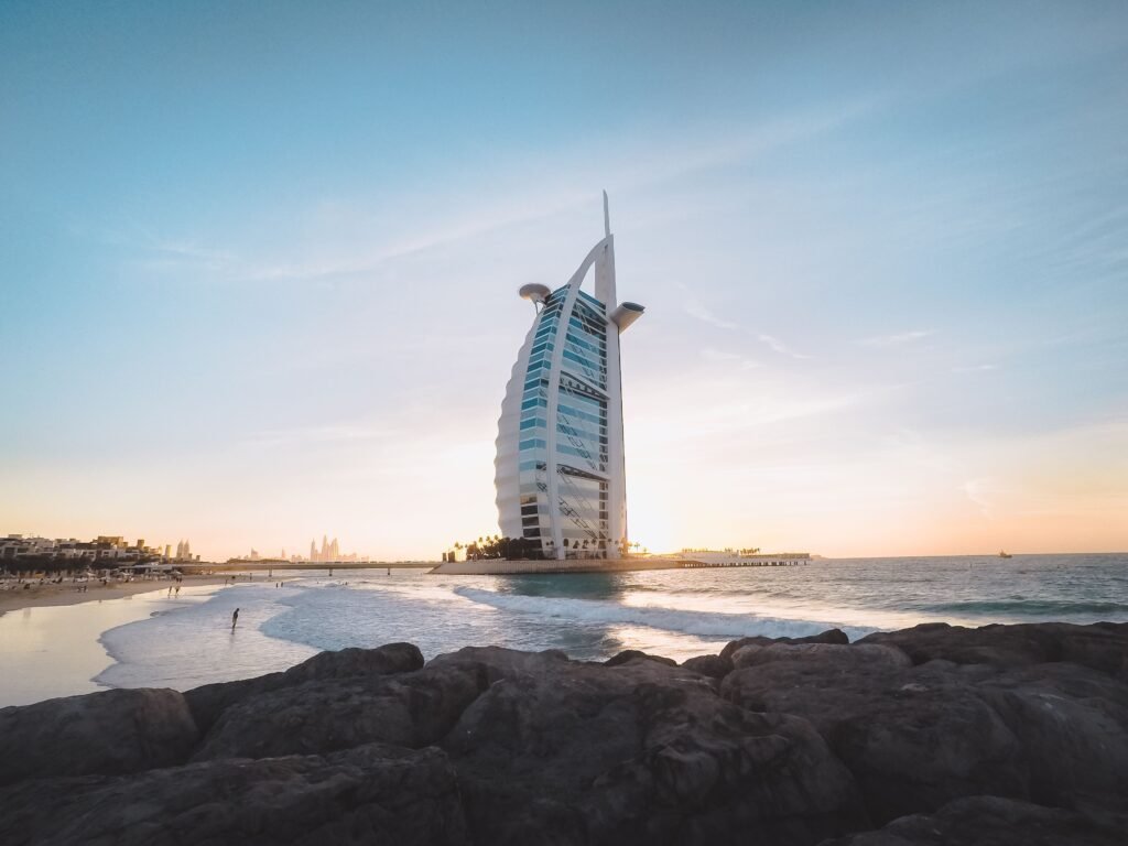 Low angle of Burj Al Arab located on sandy coast of Dubai against cloudless sundown sky