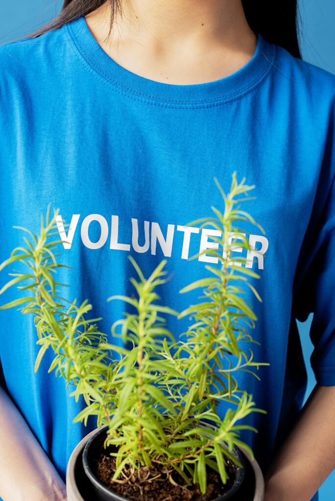 Close-up of a person holding a potted plant wearing a blue shirt with VOLUNTEER text.